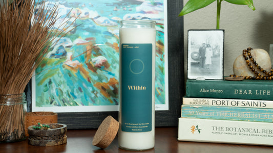Candle labeled 'Within' on a surface with books and decorative items.